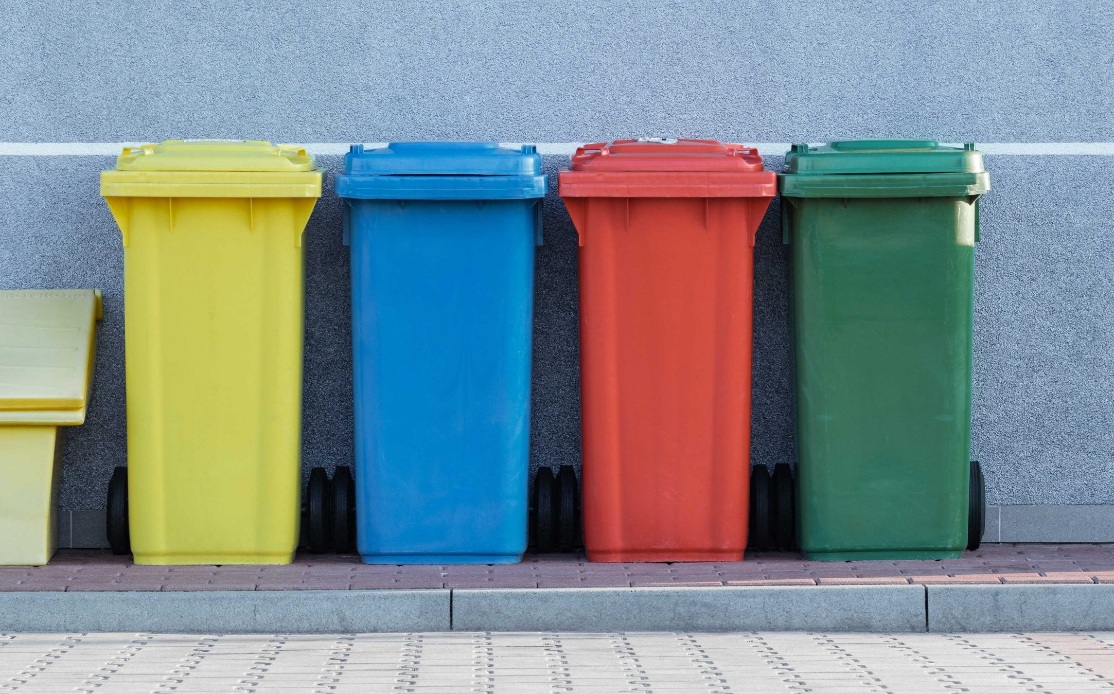 Cuatro cubos de basura con los distintos colores de reciclaje